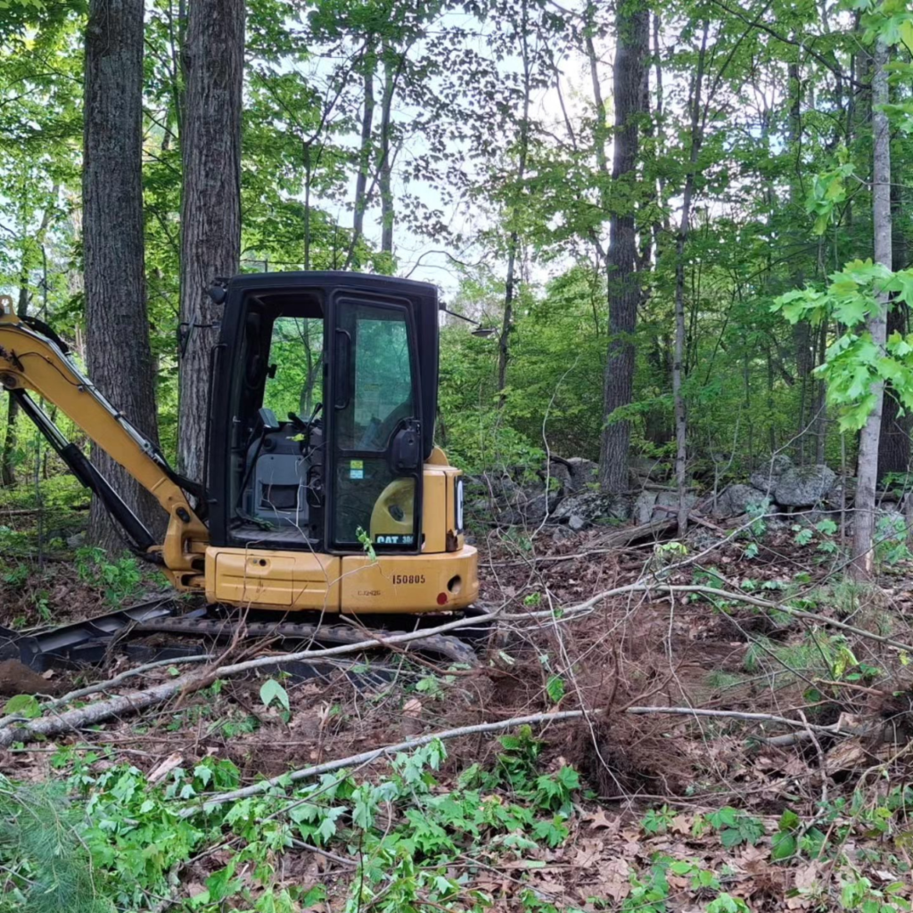 Excavator clearing brush and trees for a residential land clearing project
