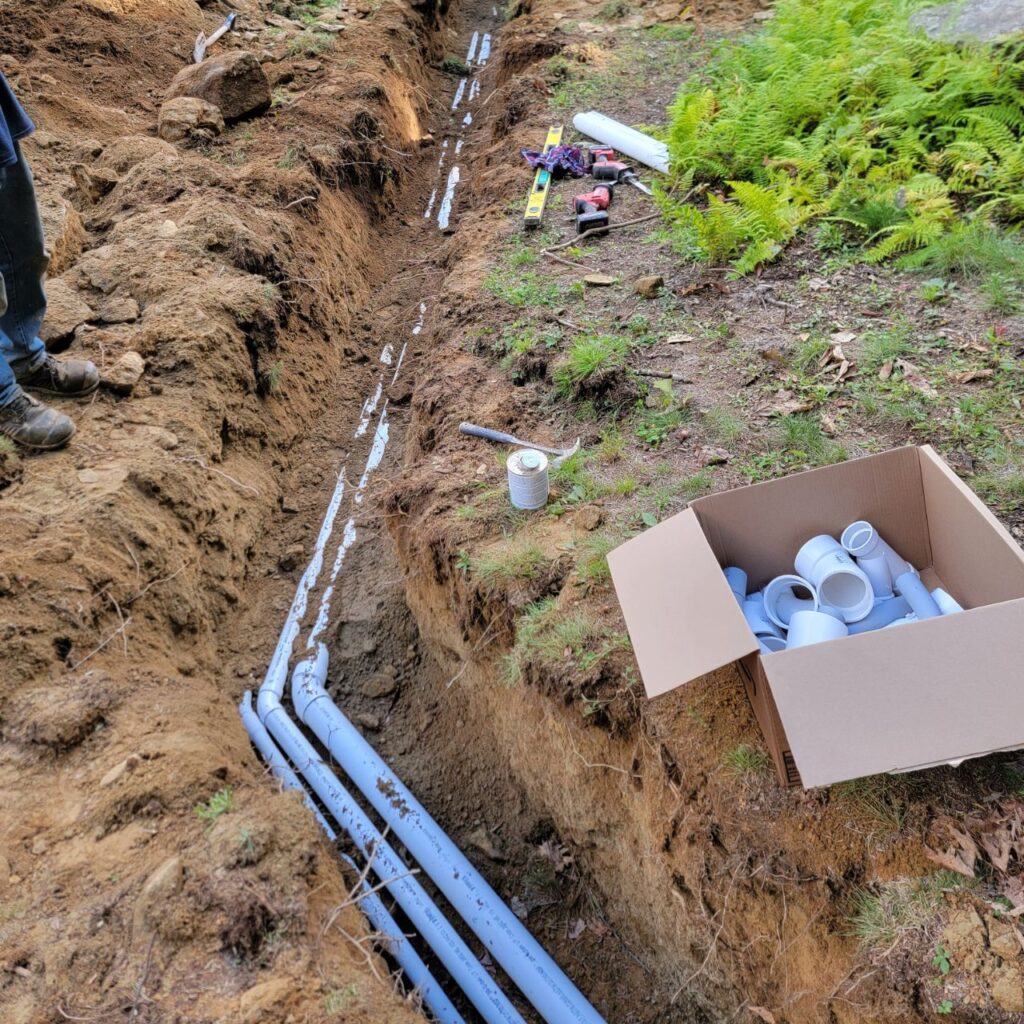 Utility trenching in Central Massachusetts with pipe set in an open trench